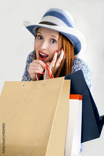 Photo: Girl holding paper-bags with purchases and talking cellphone Girl holding paper-bags with purchases and talking cellphone