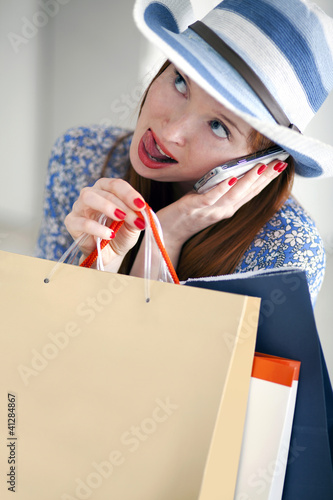 Photo: Girl holding paper-bags with purchases and talking cellphone Girl holding paper-bags with purchases and talking cellphone