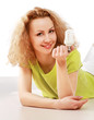 Young woman lying on floor and showing an energy-saving bulb