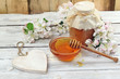 Honey in a glass jar and flower on a wooden table Honey in a glass jar and flower on a wooden table