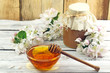 Honey in a glass jar and flower on a wooden table Honey in a glass jar and flower on a wooden table