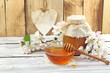 Honey in a glass jar and flower on a wooden table Honey in a glass jar and flower on a wooden table