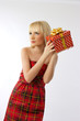 Beautiful blonde girl holding christmas gift in red dress