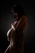 Photo: Pregnant woman over dark background Pregnant woman over dark background