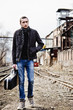 Young musician with guitar case is going among industrial ruins Young musician with guitar case is going among industrial ruins