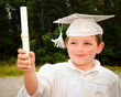 Young boy with cap and gown and certificate for graduation
