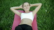 Woman in sport outfit doing sit ups in a park