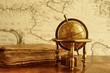 Foto: Globe and vintage book against map on a wall. Globe and vintage book against map on a wall.