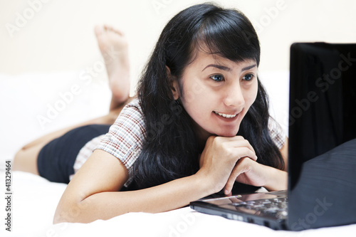 Photo: Beautiful Asian woman with laptop in bedroom Beautiful Asian woman with laptop in bedroom