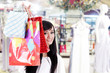 Smiling woman hiding behind her shopping bags