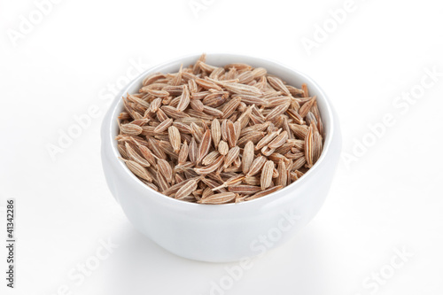 Photo: Cumin seeds in a white bowl on white background. Cumin seeds in a white bowl on white background.