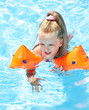 Child with armbands playing in swimming pool. Child with armbands playing in swimming pool.