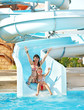 Child with mother on water slide at aquapark.