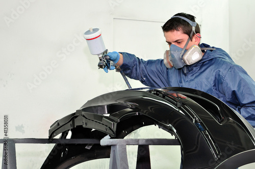Photo: Man painting a black fender. Man painting a black fender.