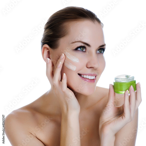 Photo: Happy smiling beautiful woman applying cream on the facem Happy smiling beautiful woman applying cream on the facem