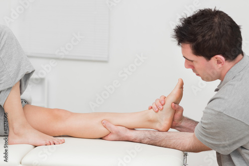 Photo: Serious doctor massaging a calf on a medical table Serious doctor massaging a calf on a medical table