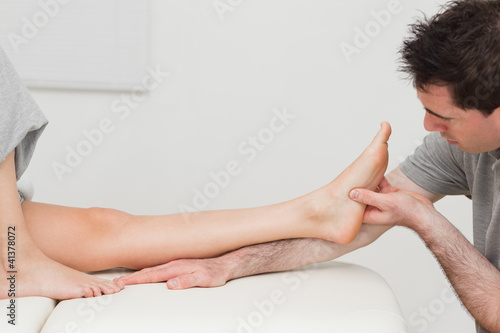Photo: Physiotherapist looking at the foot of a patient Physiotherapist looking at the foot of a patient