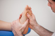 Podiatrist practicing reflexology on the foot of woman