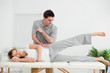 Photo: Doctor pressing his elbow on her hip while woman raising her leg Doctor pressing his elbow on her hip while woman raising her leg