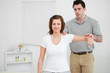 Doctor examining the shoulder of his patient while holding his a