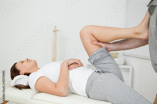 Photo: Woman putting her foot on the chest of her doctor while stretchi Woman putting her foot on the chest of her doctor while stretchi