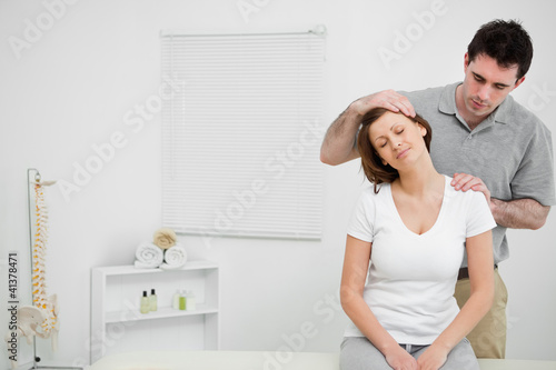 Photo: Doctor examining the neck of his patient while stretching it Doctor examining the neck of his patient while stretching it