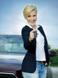 Pretty blonde woman proudly presents the key of her new car