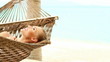 Cute woman lying on hammock on tropical beach