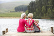Mother, daughter and grandmother sitting on a jetty