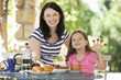 Mother and daughter eating breakfast outdoors