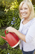 Senior woman watering garden