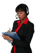 Woman wearing a headset and writing on a clipboard