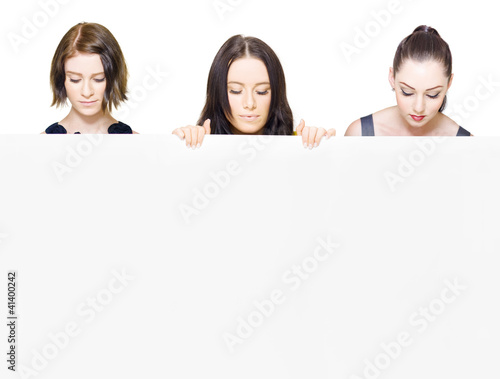 Photo: Women looking down holding a blank sign Women looking down holding a blank sign