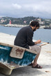 Painter painting a picture sitting on old row boat Painter painting a picture sitting on old row boat