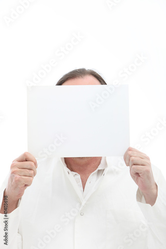 Photo: Man holding blank white paper in front of his face Man holding blank white paper in front of his face