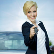 Pretty blonde woman proudly presents the key of her car