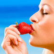 Young woman with strawberry on beach