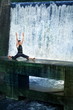 man doing the splits on  footbridge at the waterfall