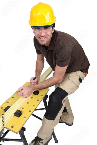 Foto: Tradesman using a plane to smooth a plank of wood Tradesman using a plane to smooth a plank of wood