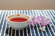 Cup of tea and cherry blossoms with lilac on bamboo table cloth