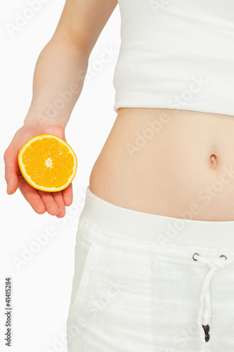 Photo: Close up of a woman placing an orange near her belly Close up of a woman placing an orange near her belly