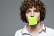 Young man with a piece of paper covering his mouth