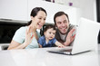 A couple and their baby son waving to someone via the internet