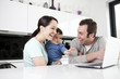 A couple and their baby son looking at a laptop