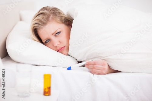 Photo: Sick blonde woman with a thermometer Sick blonde woman with a thermometer