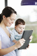 A mother and baby son looking at a digital tablet