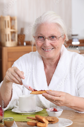 Photo: An old woman eating breakfast. An old woman eating breakfast.