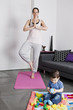 A young mother practicing yoga at home with her baby