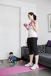 A young mother exercising at home with her baby son