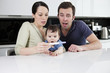 A couple and baby looking surprised at a pregnancy test result